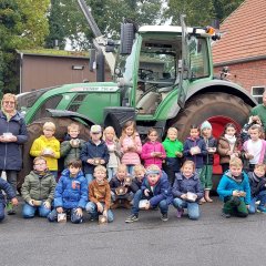 Skupinová fotografie třídy 1a před traktorem.