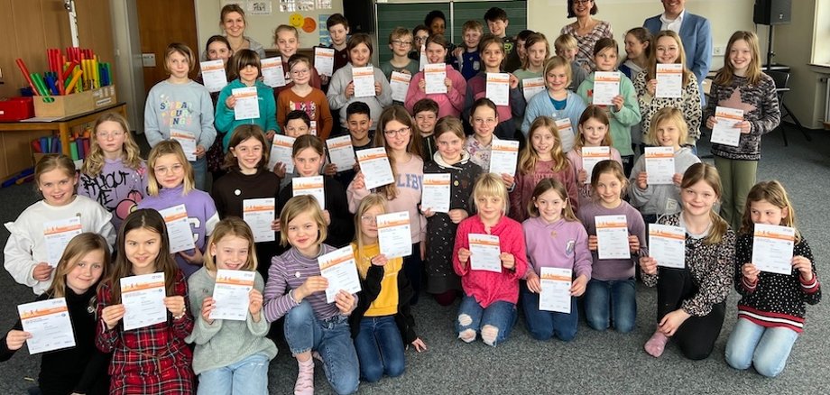 Students hold up their sports badges.