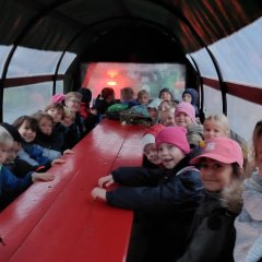 The children of class 1b and the class teacher go to the farm together in a covered wagon.