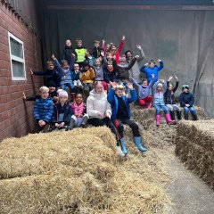 The children of class 2b take a break on hay bales at the farm.