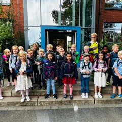 The children of the first class (1a) with their class teacher in front of the main entrance of the George School.