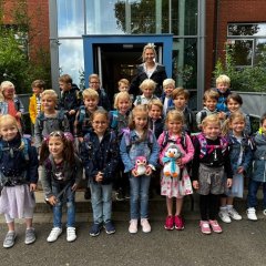 The children of the first class (1b) with their class teacher in front of the main entrance of the George School.