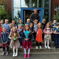 The children of the first class (1c) with their class teacher in front of the main entrance of the Georg School.