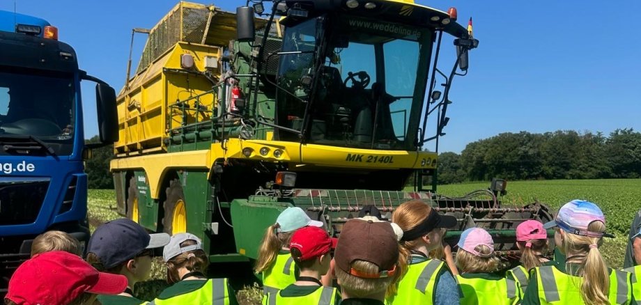 Children stand in front of a spinach harvester