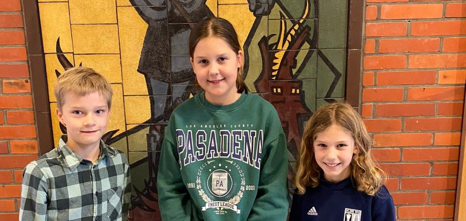 The class winners of the reading competition Jonathan Nollmann (4c), Paula Klöpper (4a) and Tilda Weinberg (4b) stand in front of the mosaic of St. George.
