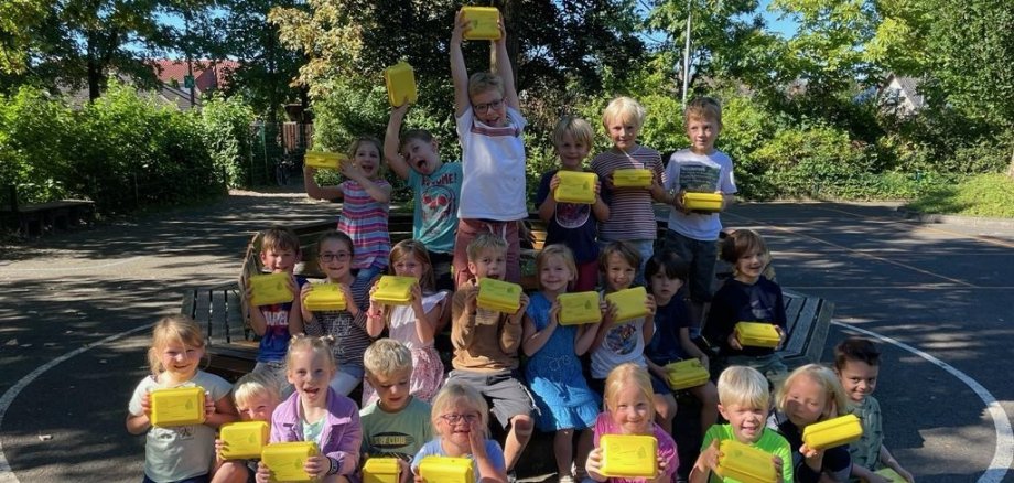 Los niños de la clase Punguin sostienen sus nuevas paneras y se ríen ante la cámara.