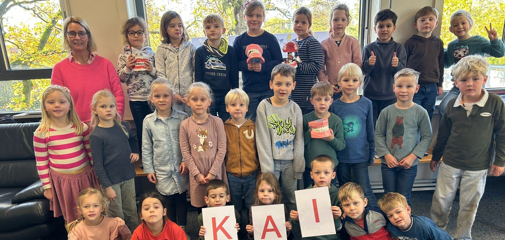 Les enfants de la classe des hiboux brandissent des pancartes pour la méthode "KAI".