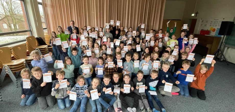 Grupinė nuotrauka, kurioje vaikai išdidžiai prieš fotoaparatą laiko savo sportinius ženklelius.