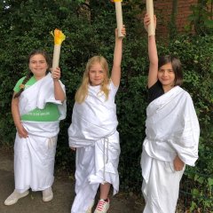 Kinderen houden een (handgemaakte) Olympische fakkel omhoog.