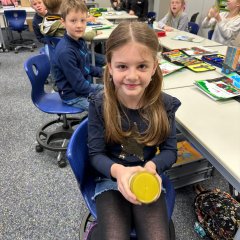 Uma criança agita um copo com tampa de rosca com natas até obter manteiga.